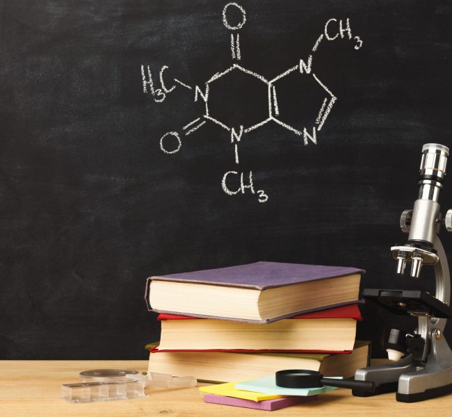 Studying chemistry educational background. Microscope, books and colorful liquids at classroom blackboard with chalk drawing of molecular structure. Back to school, experiment and research concept