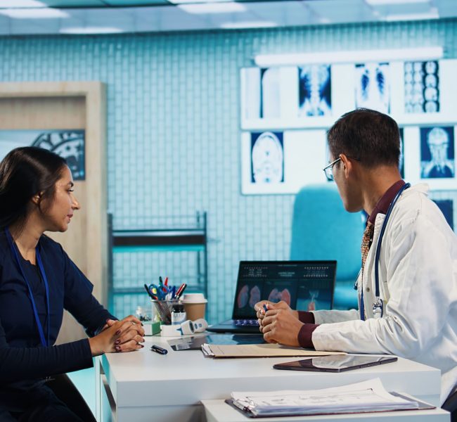Indian general practitioner and patient engage in a medical consultation with diagnostic tools and x ray text results for scan interpretation. Showcasing healthcare practices and research. Camera B.